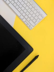 Tablet and keyboard on yellow table.