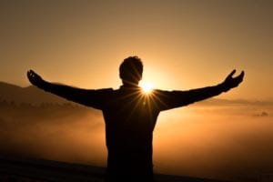 Man with arms spread at sunset.